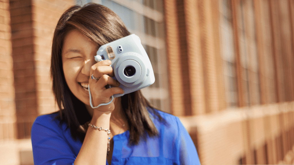 Mulher sorridente tirando foto com câmera no rosto