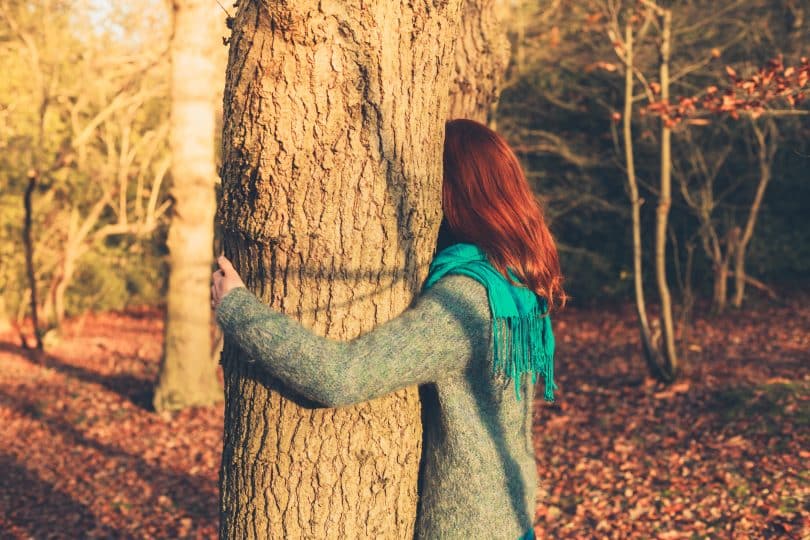Mulher abraçando uma árvore.
