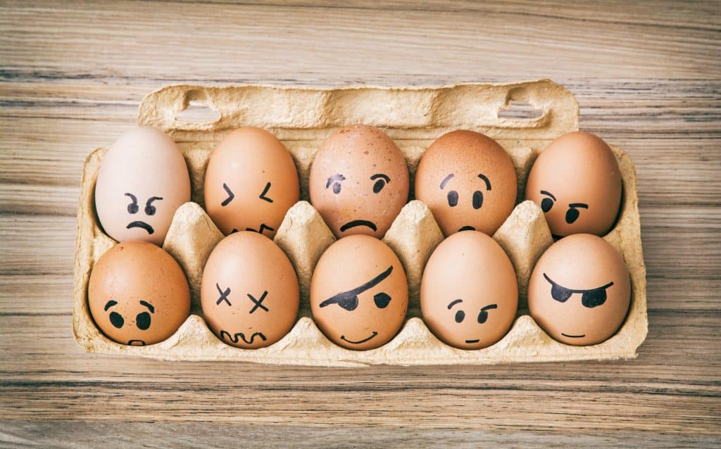 Ovos pintados de cara de emoção em caixa de papel. 