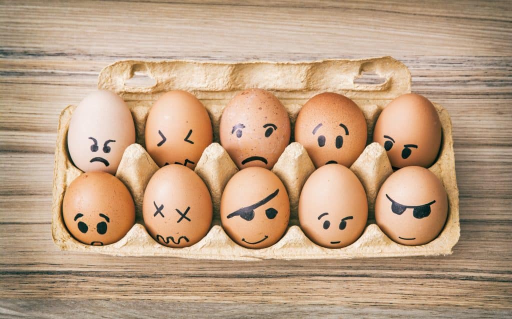 Ovos pintados de cara de emoção em caixa de papel.