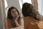 Uma mulher contemplando sua própria imagem num espelho.