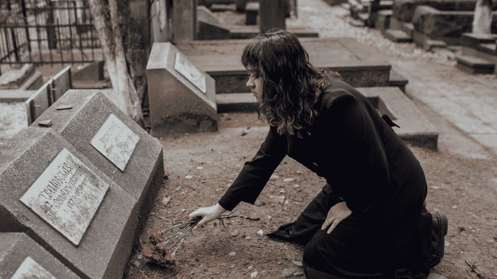Uma mulher colocando flores sobre um túmulo.
