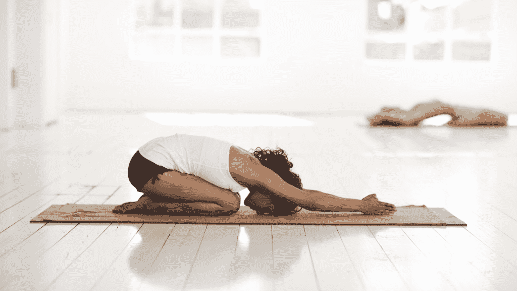 Mulher em cima de tapete de yoga praticando uma posição