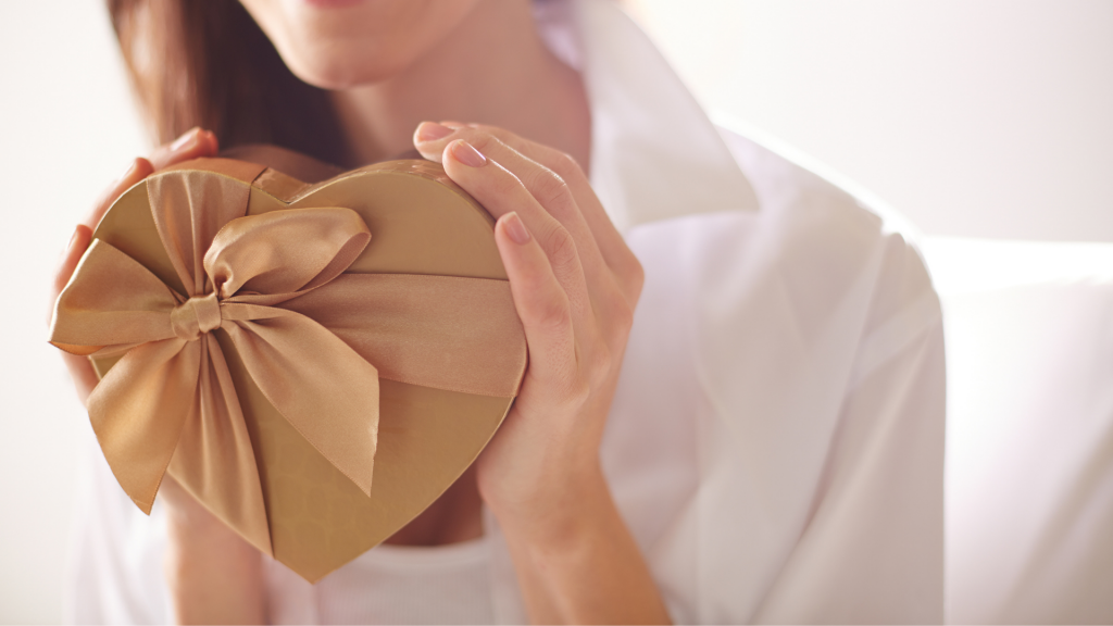 Mulher segurando uma caixa de presente dourada, em formato de coração