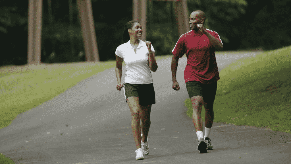 Homem e mulher fazendo uma caminhada e sorrindo um para o outro