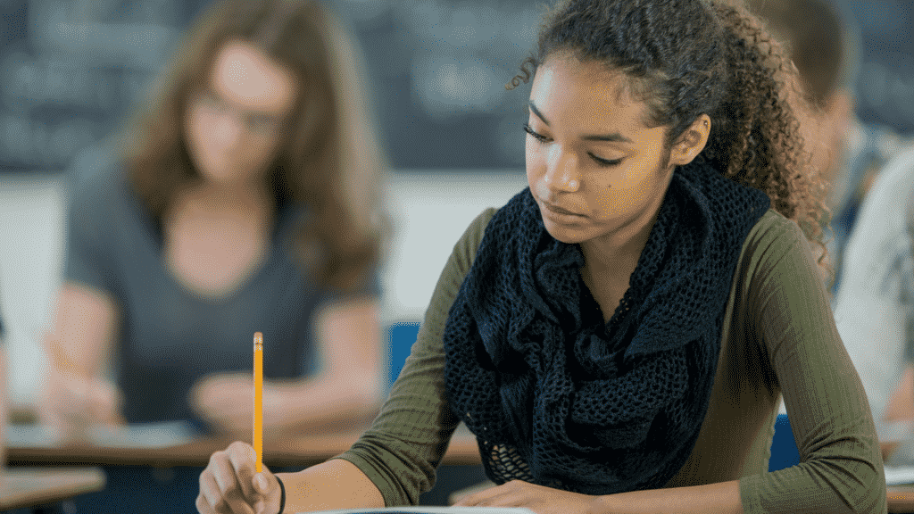 Menina fazendo uma prova com outros estudantes em uma sala