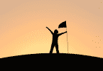 Pessoa segurando uma bandeira no topo de uma montanha