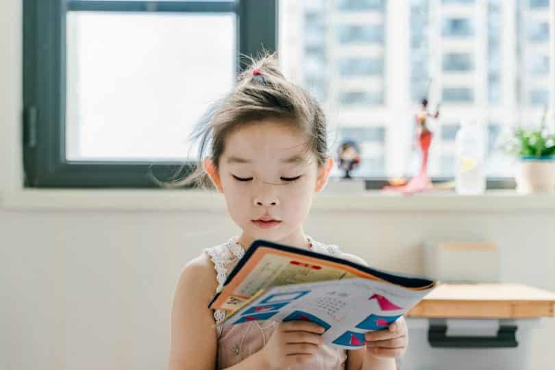Criança asiática lendo livro.