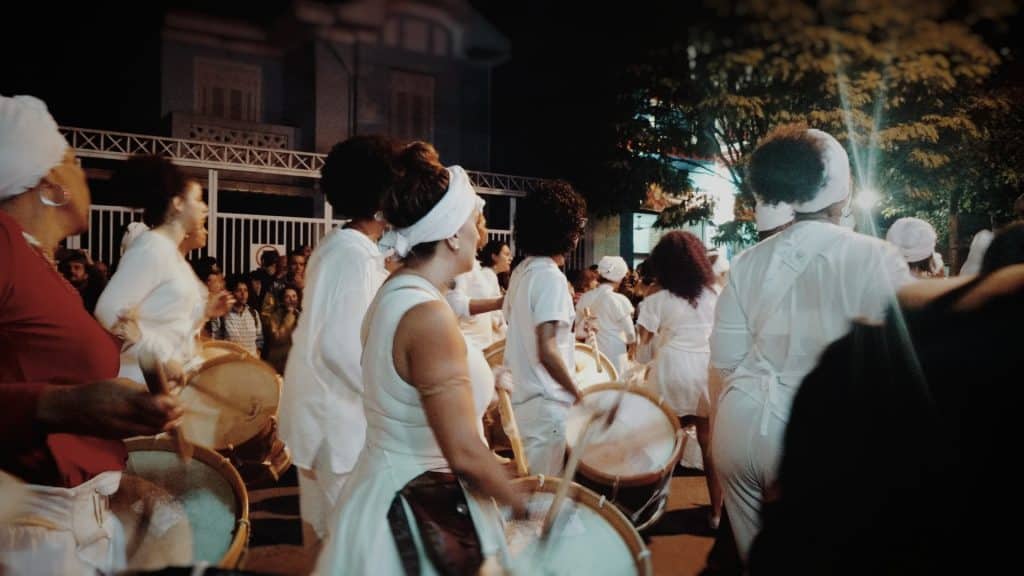 Pessoas de roupas brancas tocando instrumentos.