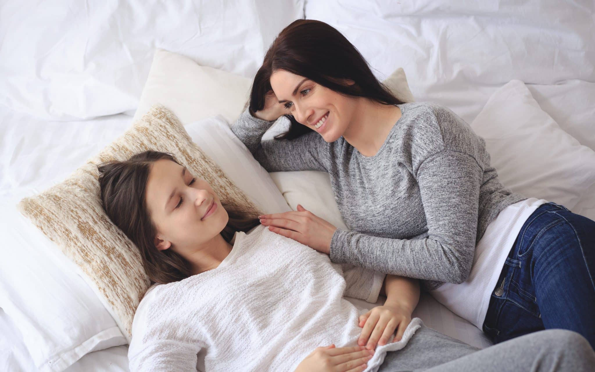 Uma mulher e a sua filha deitadas numa cama. 