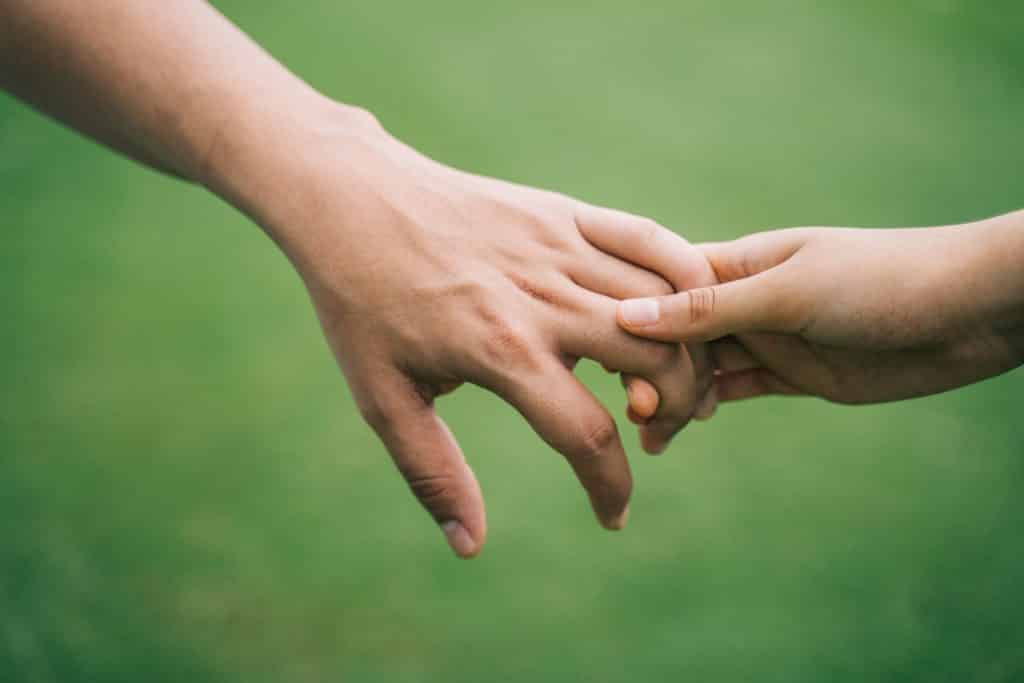 Pessoa segurando a mão de uma criança