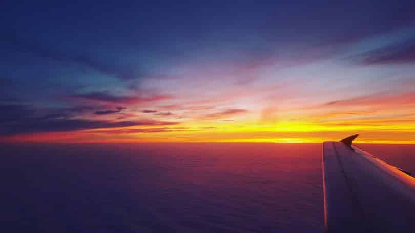 Avião voando em frente ao pôr do Sol