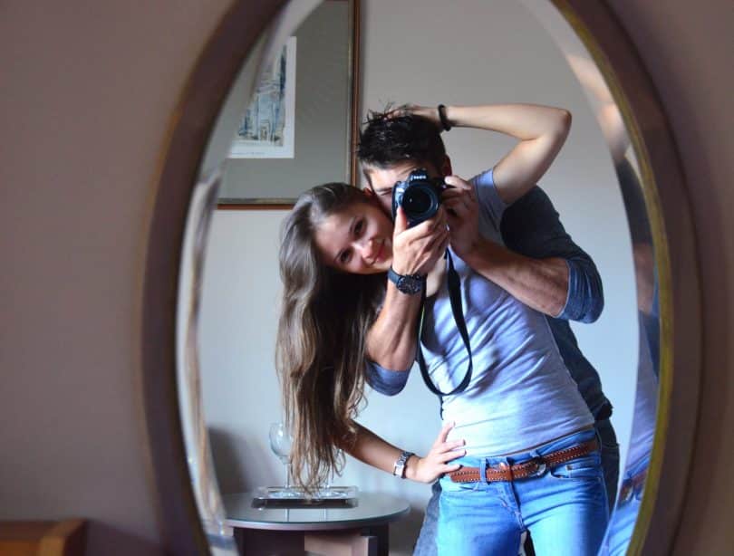 Homem e mulher tirando foto no espelho