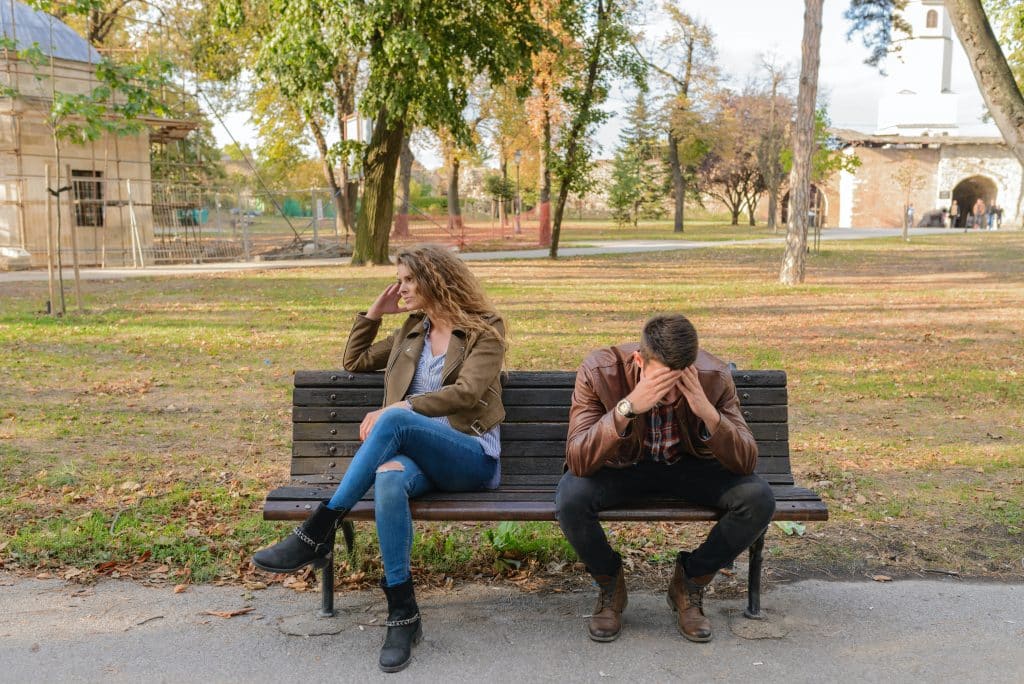 Homem e mulher sentados em um banco da praça 