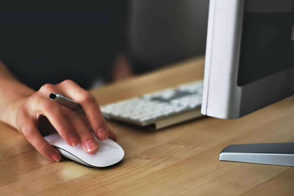 Mulher em frente ao computador com a mão sobre um mouse 