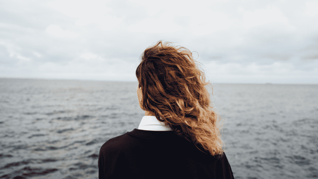 Uma mulher contemplando um grande mar.