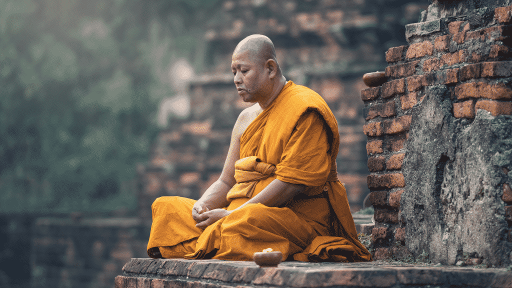 Um homem trajando vestes budistas e meditando.