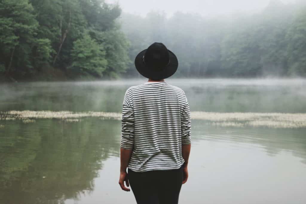 Pessoa de costas perto de um lago.
