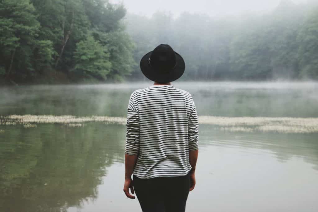 Pessoa de costas perto de um lago.