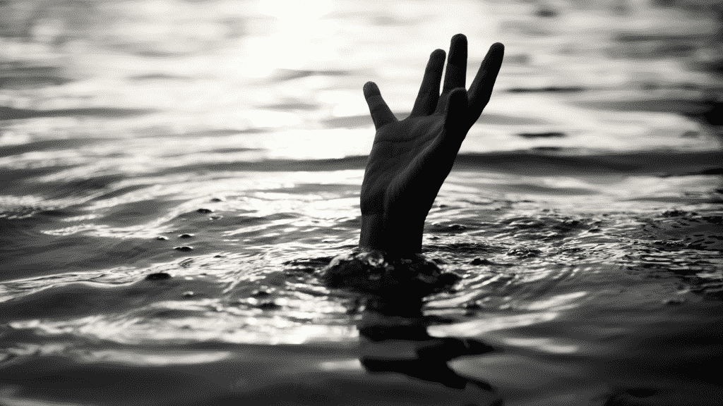 Uma mão erguida se sobressaindo à água.