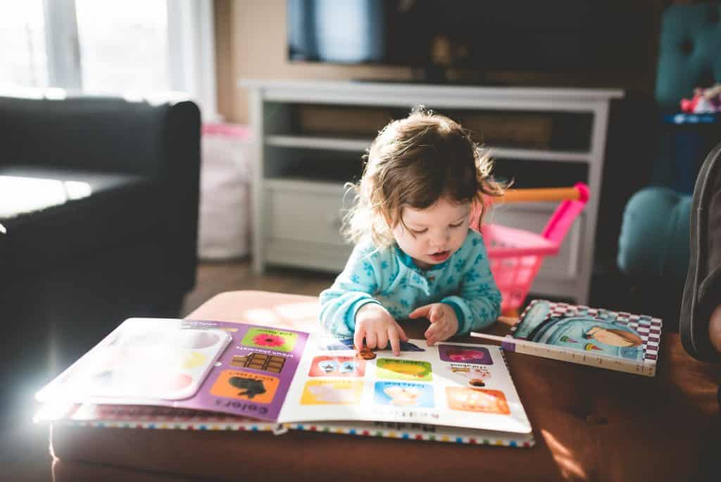 Criança branca lendo livro.