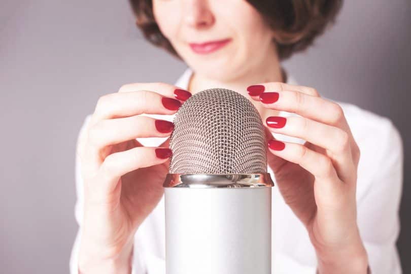 Uma mulher colocando suas mãos sobre um microfone de lapela.