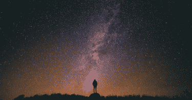 silhueta de pessoa observando o céu noturno estrelado