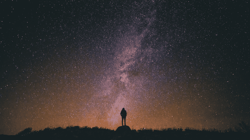 silhueta de pessoa observando o céu noturno estrelado