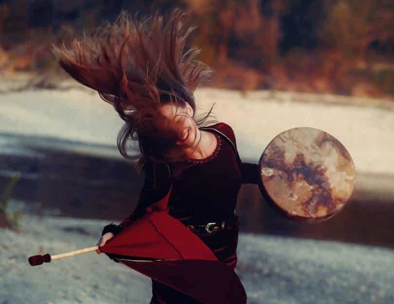 Mulher tocando um tambor e jogando o cabelo para o ar.