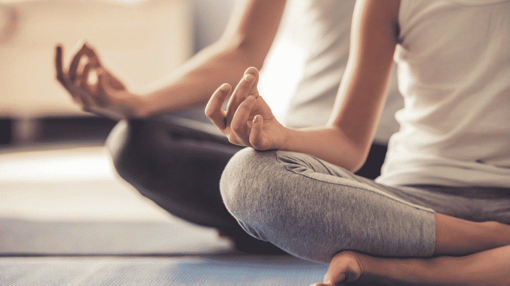 Pessoas sentadas com as mãos em cima de cada joelho, meditando