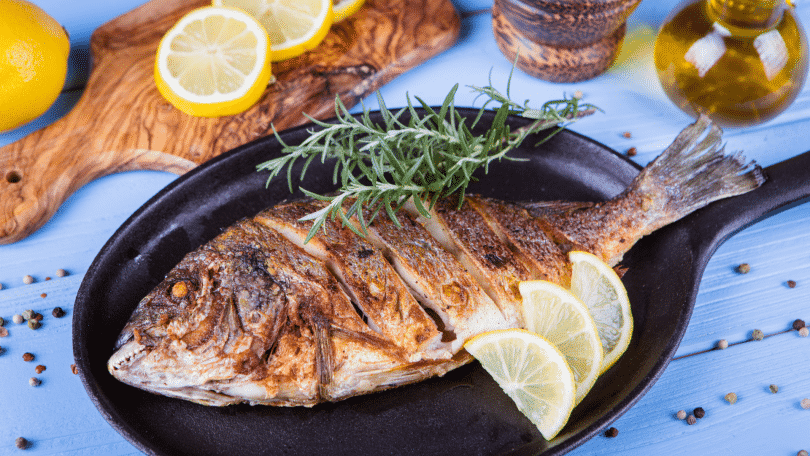 Peixe assado com limão fatiado e alecrim