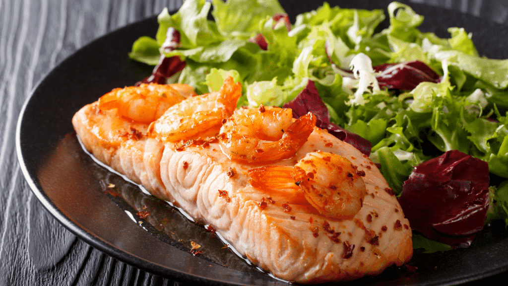 Prato com peixe assado, camarão e salada