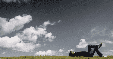 Pessoa deitada em um gramado, olhando para o céu