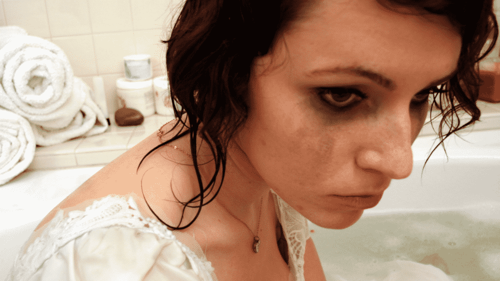 Menina com a maquiagem borrada dentro de uma banheira com água