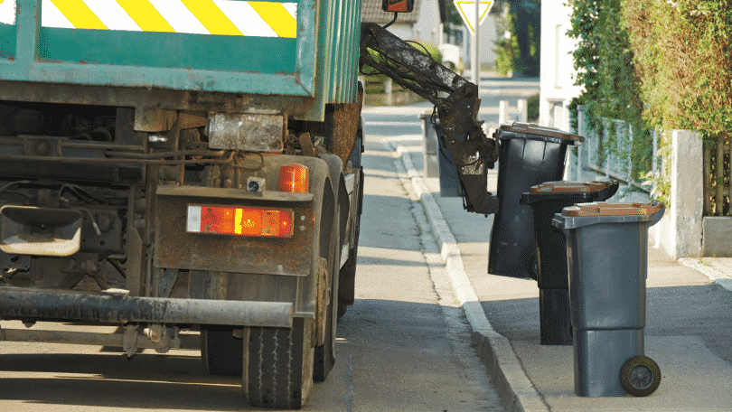 Caminhão compactador coletando lixo