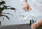 Pessoa colocando água de uma jarra em um copo d'água