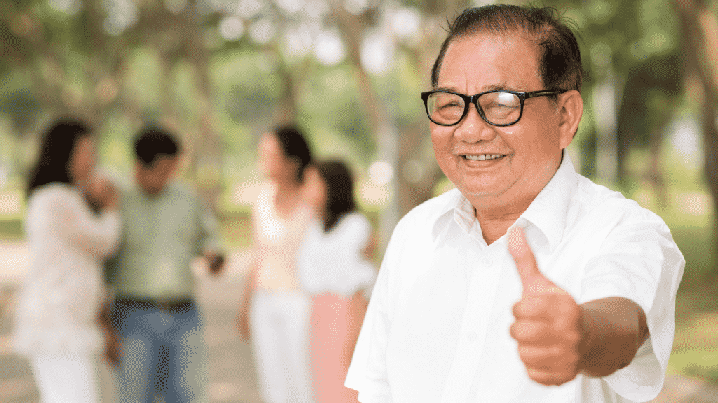 Homem asiático de idade sorrindo e dando um joinha para a foto