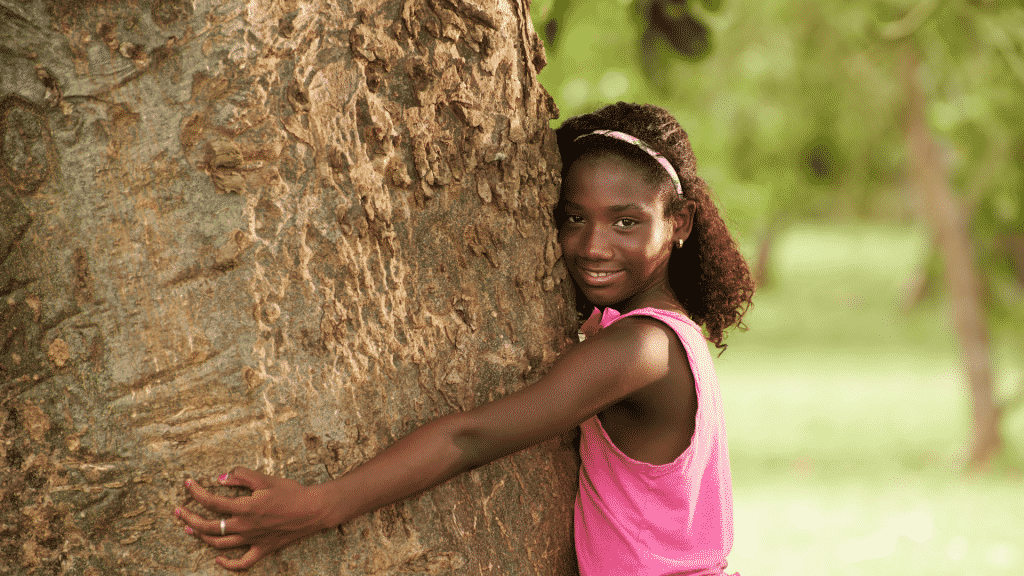 Menina abraçando uma árvore e sorrindo