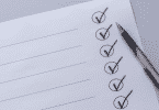 Imagem de um caderno de checklist e uma caneta ao lado