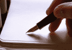Pessoa escrevendo em um papel branco com uma caneta de ponta fina