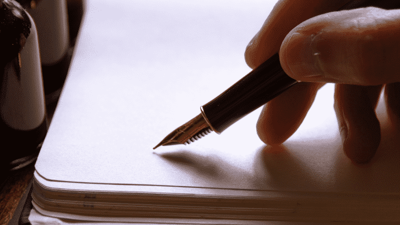 Pessoa escrevendo em um papel branco com uma caneta de ponta fina