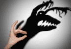 Mão fazendo sombra em uma parede. A sombra está aparecendo diferente, na forma de um monstro