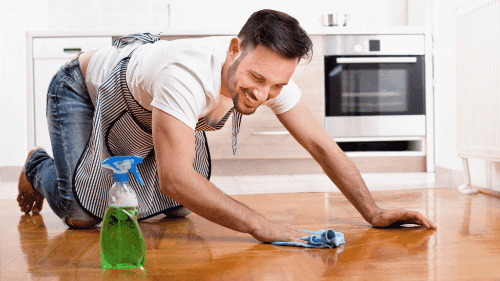 Um homem limpando o chão de sua casa com um pano.