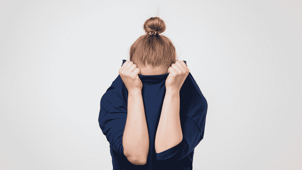 Uma mulher escondendo seu rosto numa blusa de frio.