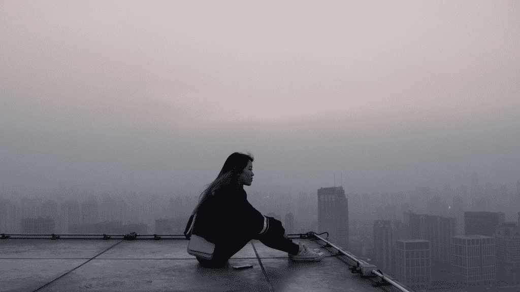 Uma mulher asiática sentada num topo de um prédio.