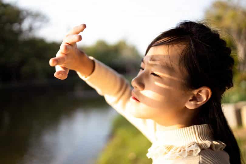 Uma mulher asiática sendo iluminada pelo sol.