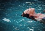 Menina boiando na piscina.