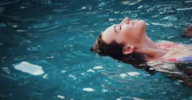 Menina boiando na piscina.