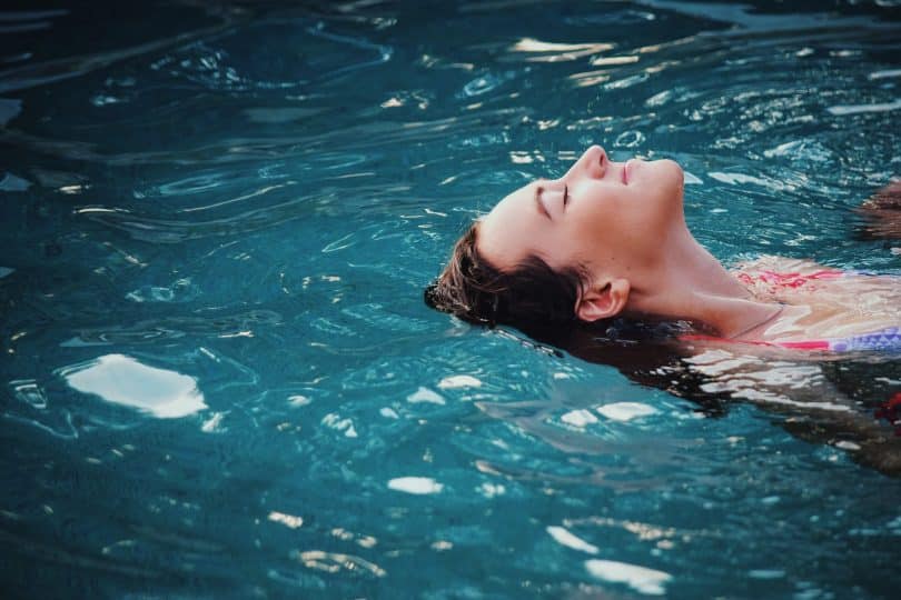 Menina boiando na piscina.