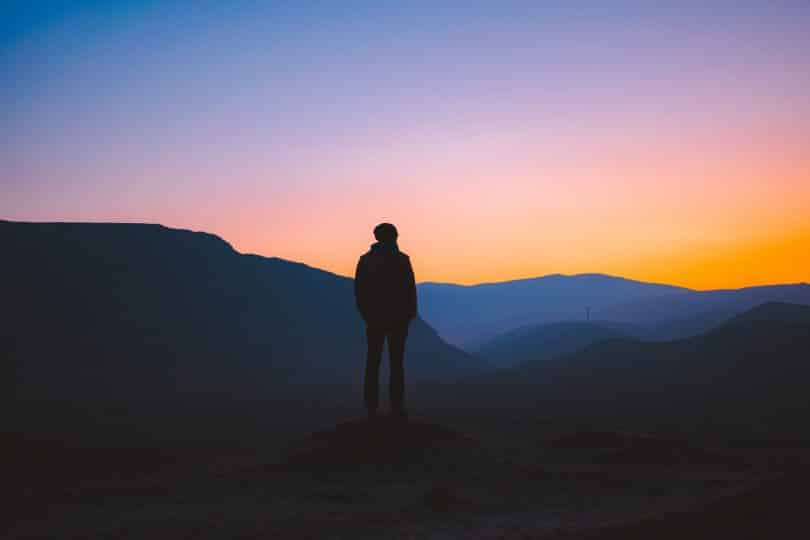 Homem de costas num pôr do sol.